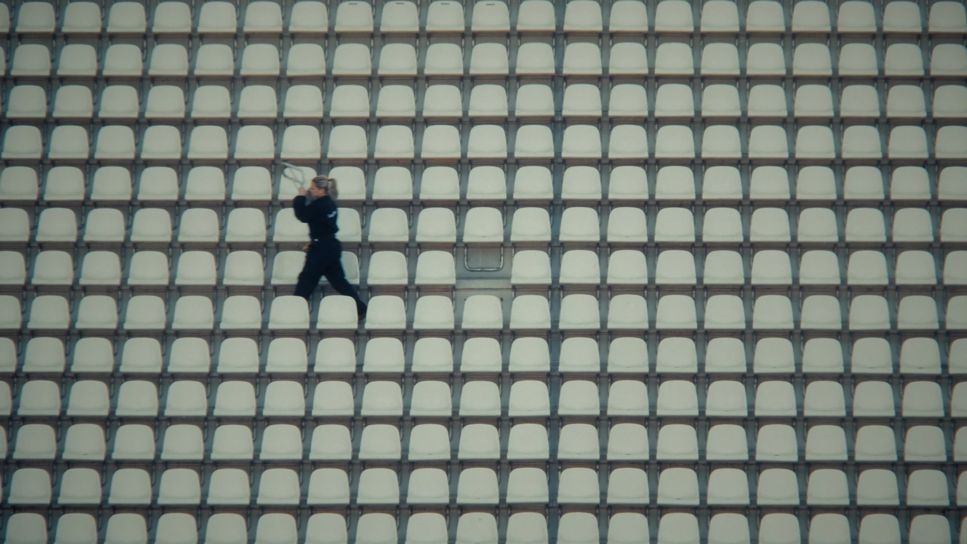Une femme court entre les rangées de sièges du stade.