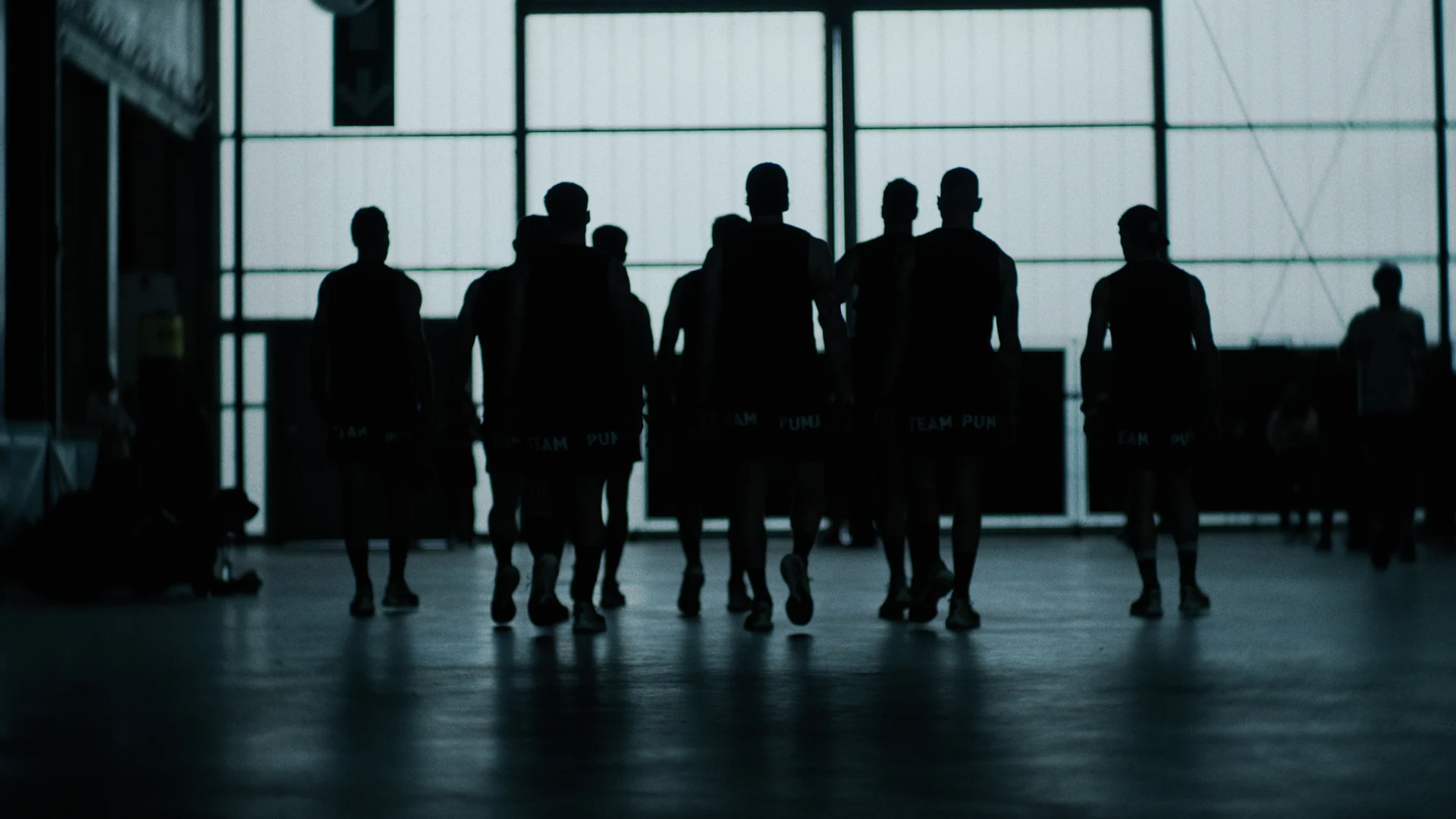 Les silhouettes de la team Puma devant les baies vitrées.